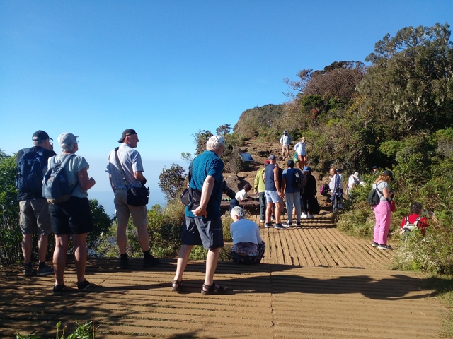 Tourists on a cliff edge at a scenic viewpoint.