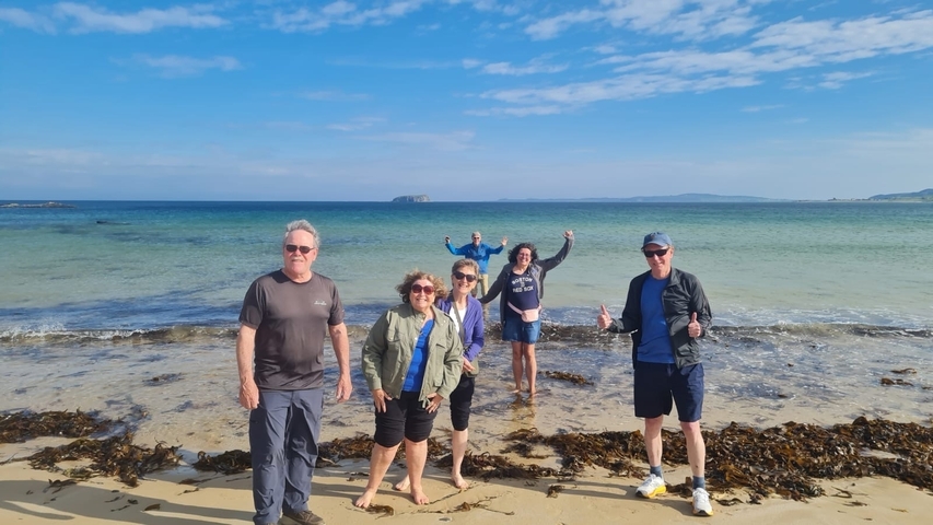 Group of people on a beach with clear blue ocean.