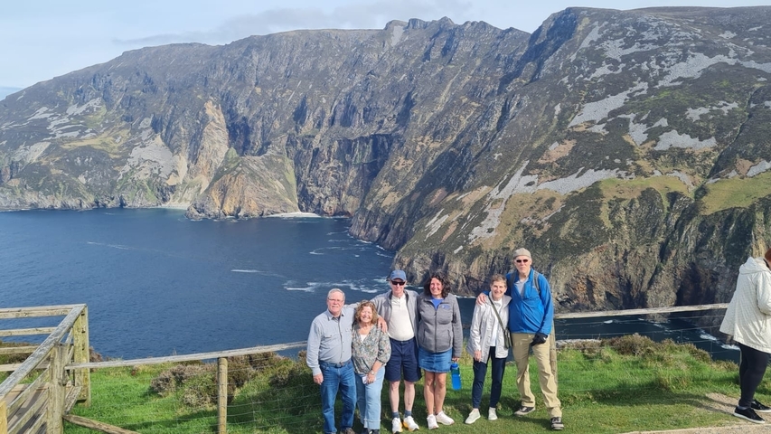 Group of people with a scenic coastal cliff background.