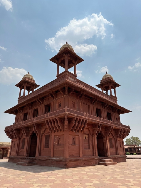 Ornate red sandstone building with domes and balconies.