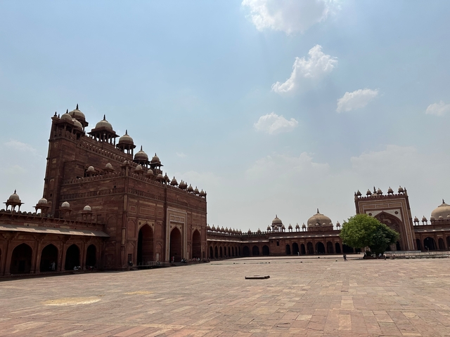       Courtyard with large red sandstone building with arches.
  