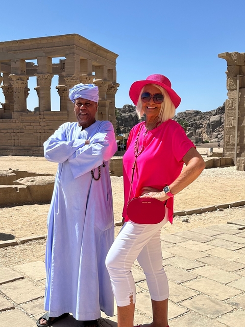 Two people smiling and posing in front of ancient ruins.