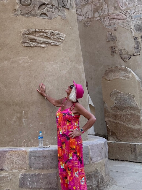       Woman posing against ancient stone walls.
  