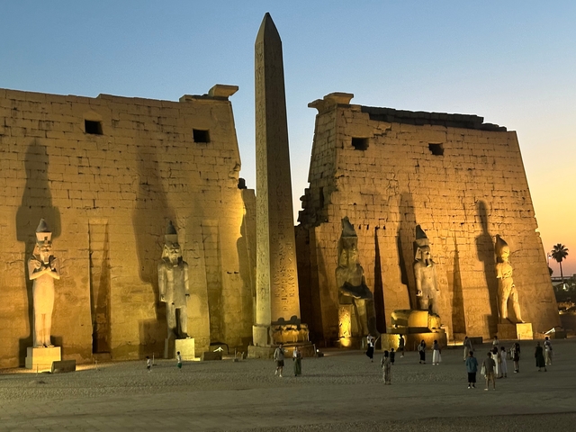       Lit-up ancient temple during twilight with tourists around.
  