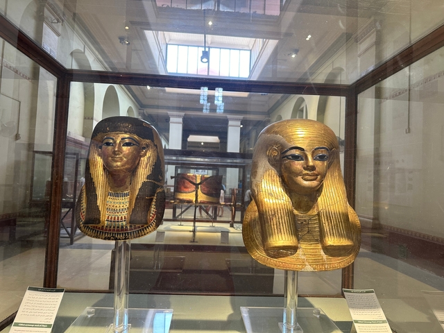 Two sarcophagi masks displayed in a museum setting.