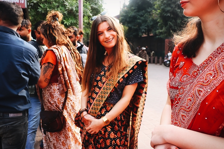 Smiling woman in traditional attire among a group of people.