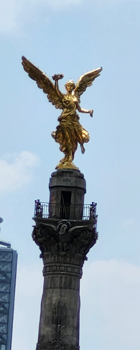 Close-up photo of a golden statue on a pillar.
