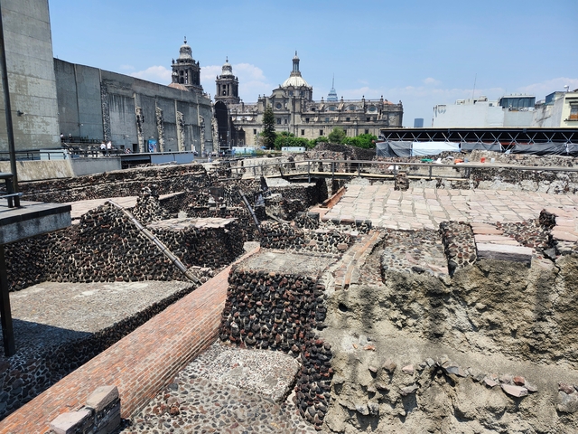       Ancient ruins with a city skyline in the background.
  