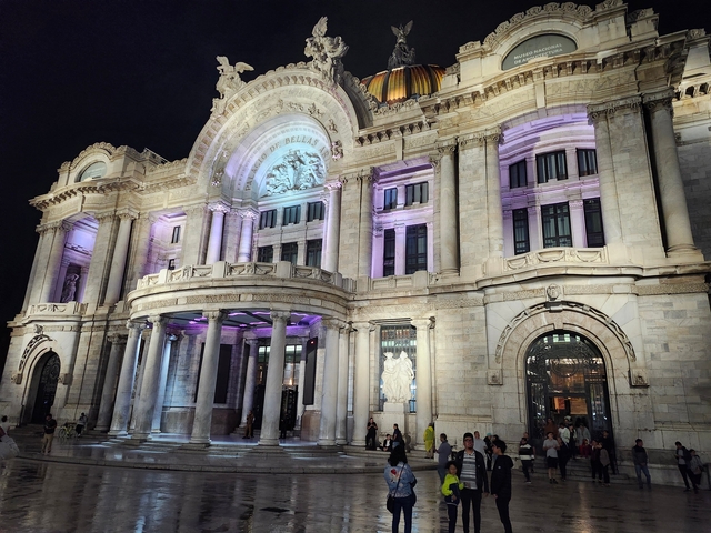 Illuminated palace with people in front.