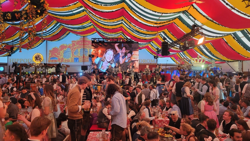 Inside a vibrant festival tent with many attendees.