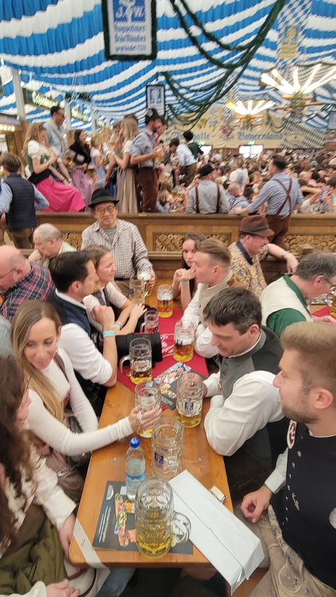 People gathered at a beer festival with large mugs of beer.