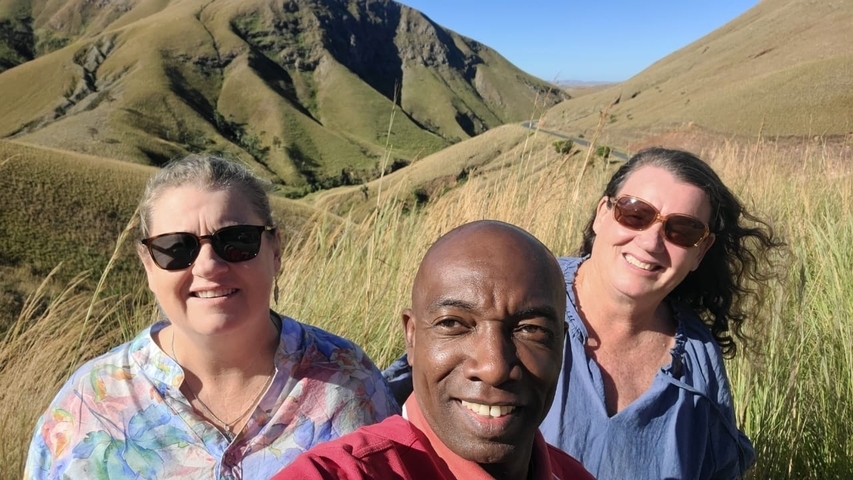       Three people taking a selfie with a hilly landscape in the background.
  