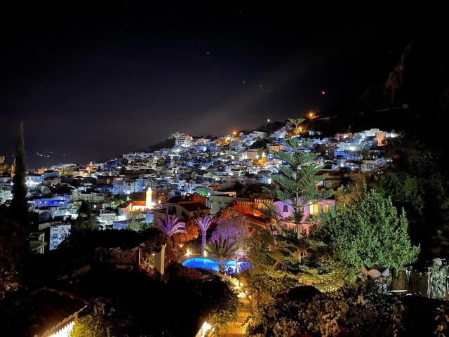 Night view over Chefchaouen with blue and white buildings.