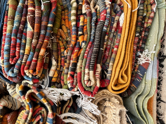 Array of colorful woven carpets or textiles.
