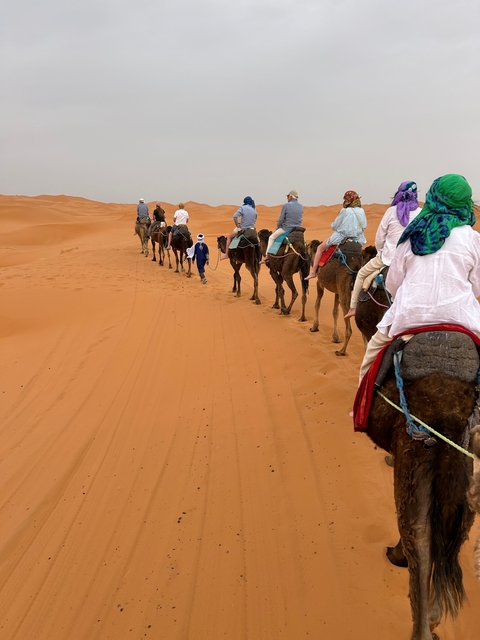 Camel caravan with travelers in the desert.