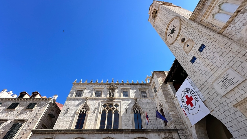 Historic stone building with clock tower against a blue sky.