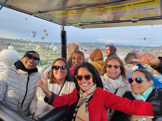       A group of people in a hot air balloon with balloons in the sky.
  