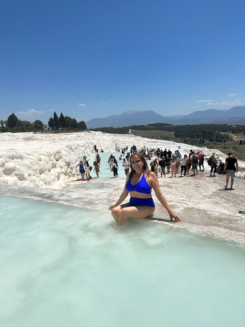       Woman posing at thermal pools with many visitors around.
  