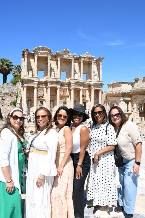       Women posing in front of ancient ruins.
  