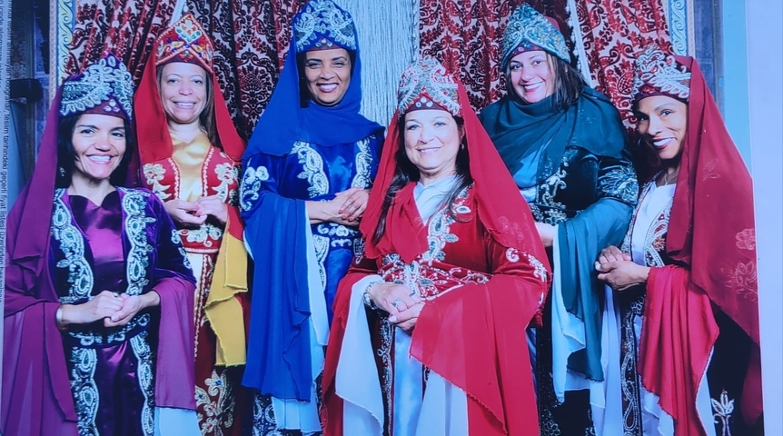Women in colorful traditional dresses posing together.