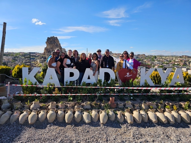       Group standing by large sign with landscape view.
  