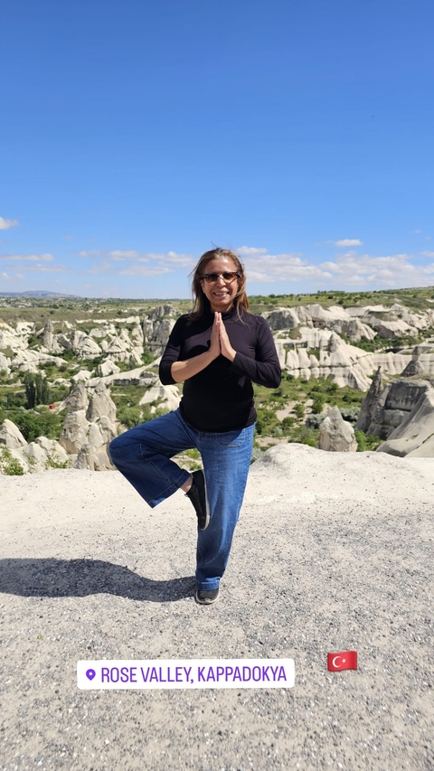 Woman striking a yoga pose with a rocky landscape behind.