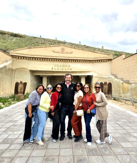       Group posing in front of a cultural entrance building.
  
