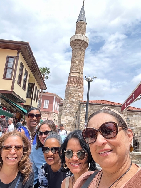       Group of women with an ancient tower in the background.
  