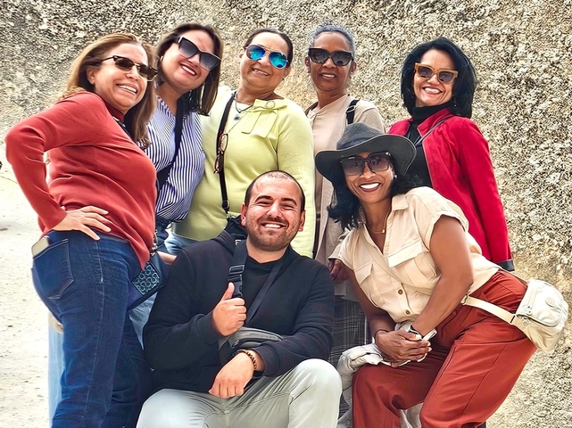       Group smiling with a stone background, likely a tour.
  