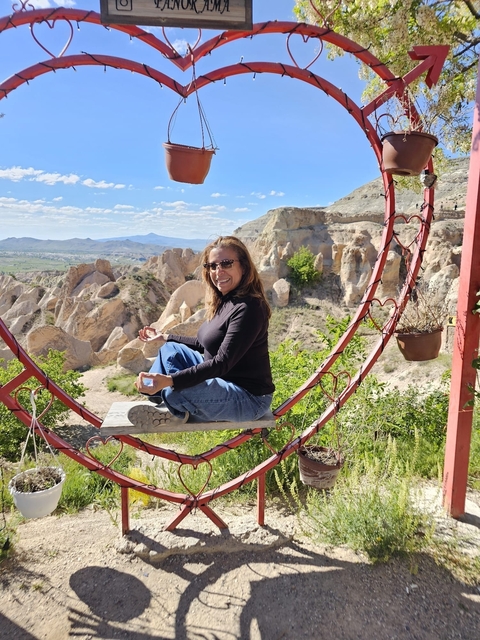       Woman sitting on a swing with rock formations behind.
  