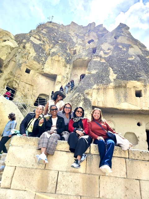       Group of women sitting on stone steps of ancient rock structures.
  