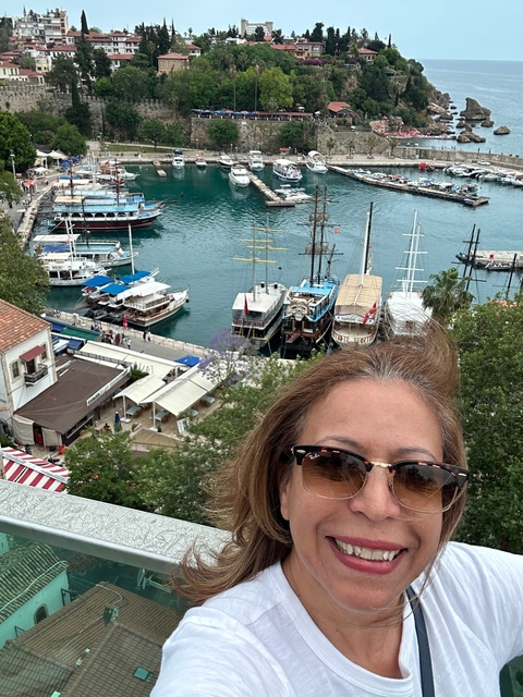Woman taking a selfie with boats in the harbor.