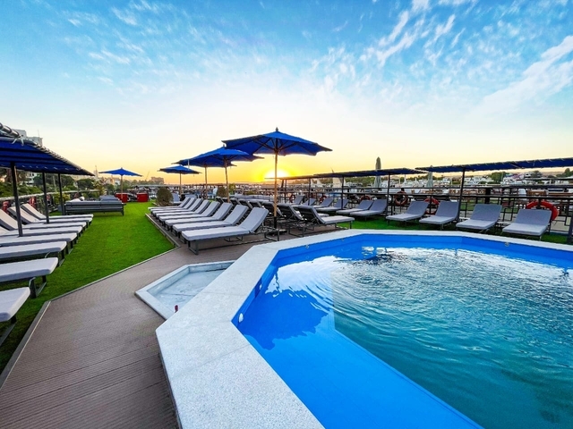 Poolside scene with loungers and umbrellas under a sunset sky.