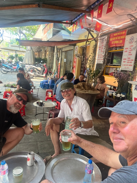 Men enjoying drinks at a street-side eatery.