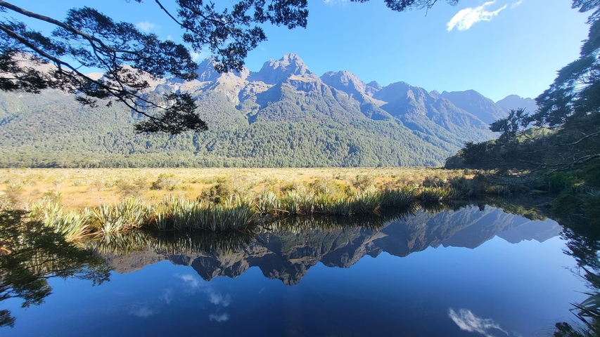       A mountain range reflected in a calm body of water.
  