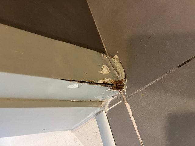       Close-up of peeling paint and damage on a doorframe.
  