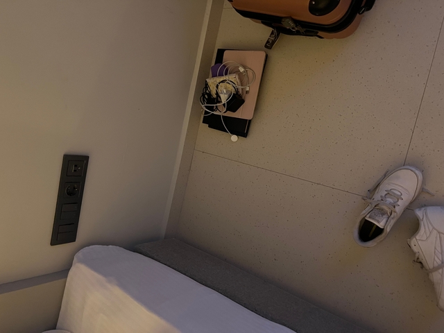       View of a room corner with personal items on the floor.
  