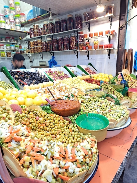 Display of various types of olives and pickles in a market.
