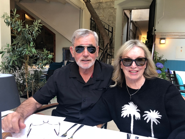 Portrait of a couple wearing sunglasses at an outdoor cafe.