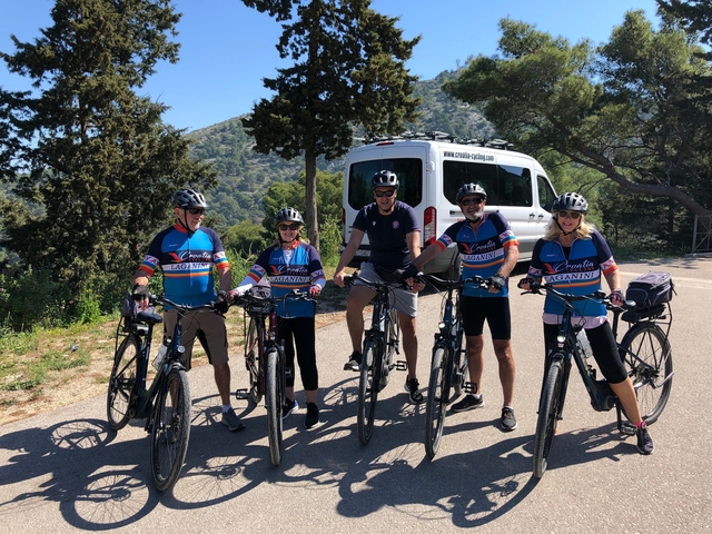 Group of cyclists posing on a sunny road with scenic background.