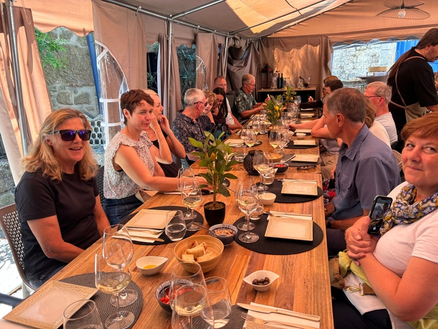 Group of people dining at a long table outdoors.