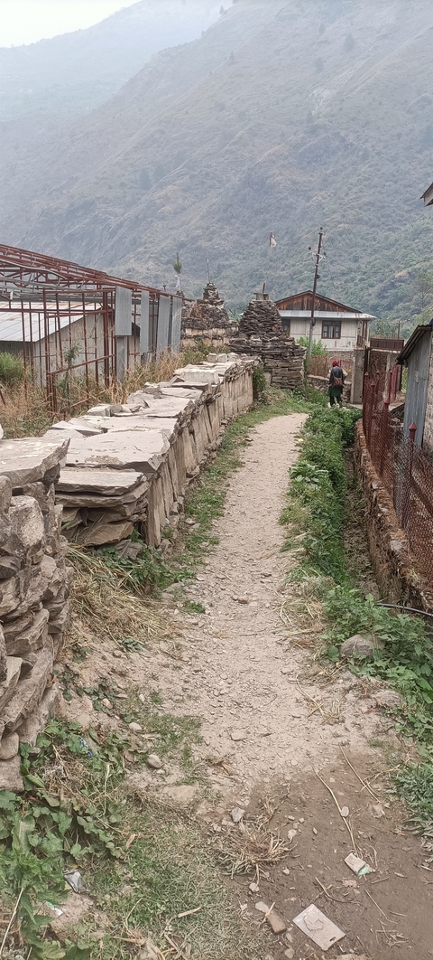 A narrow path lined with stone walls with a person walking.