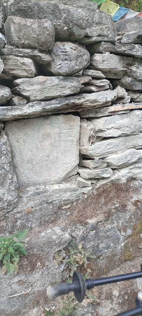 Carved stone depicting a figure, possibly a deity, on a stone wall.
