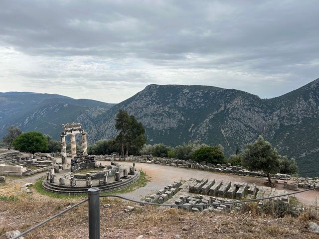Ancient ruins of a circular temple with mountains in the background.