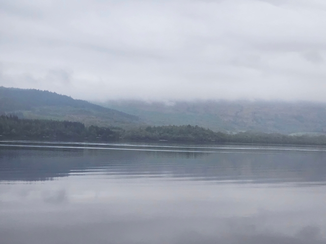 Misty mountainous landscape reflected on a calm lake.