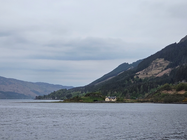      Remote house by a lake surrounded by hills.
  