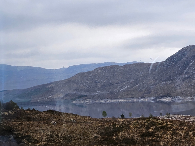 Hilly landscape with vast fields and a lake.
