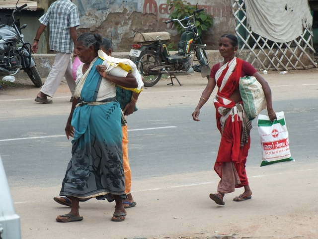       Women walking down a street carrying bags.
  