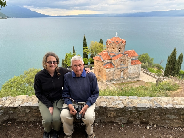 Couple sitting in front of a historic church by a lake.