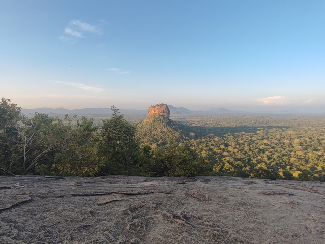 A distant view of Lion Rock amidst a vast forest landscape.